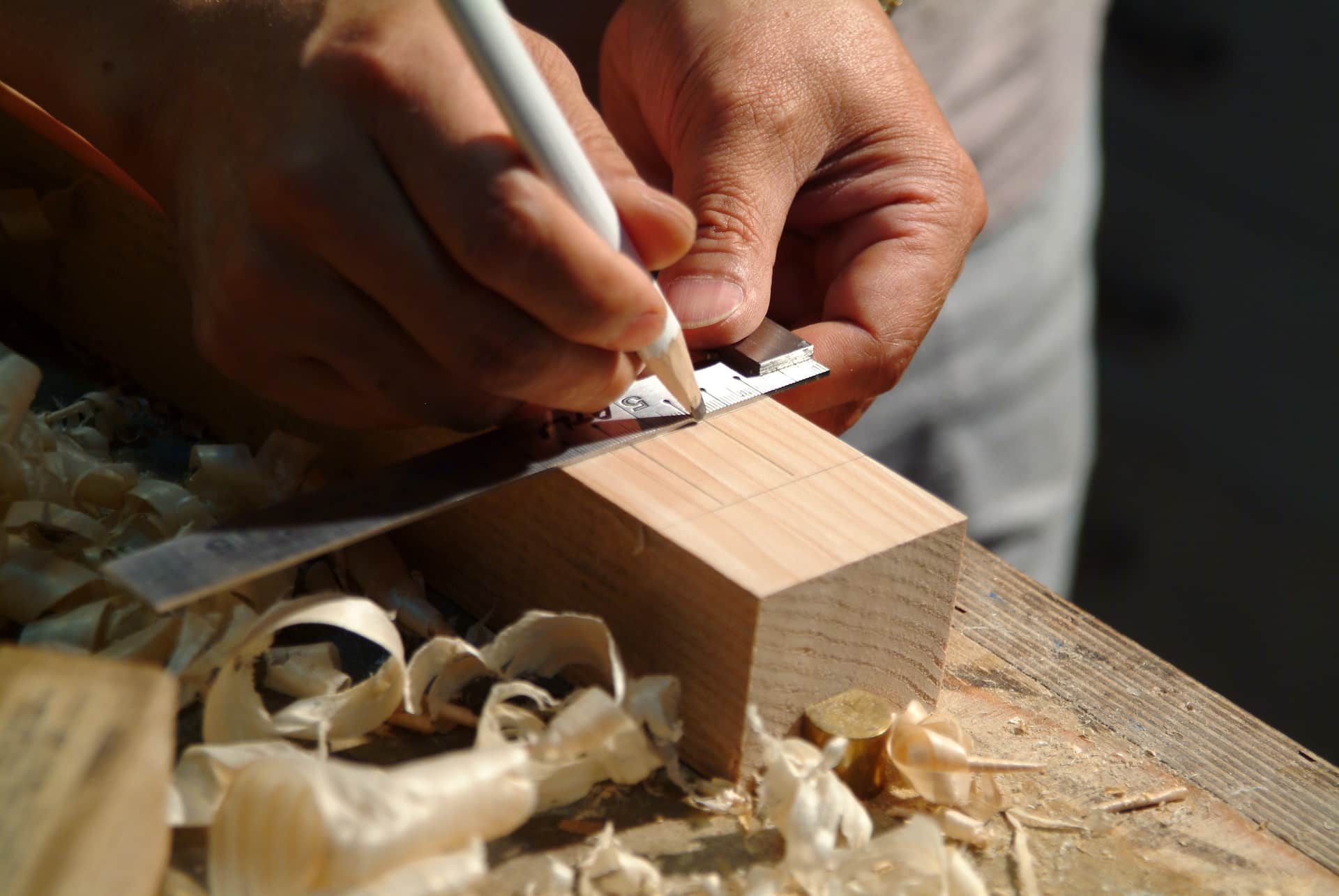 Hands marking a measurement on a wooden plank