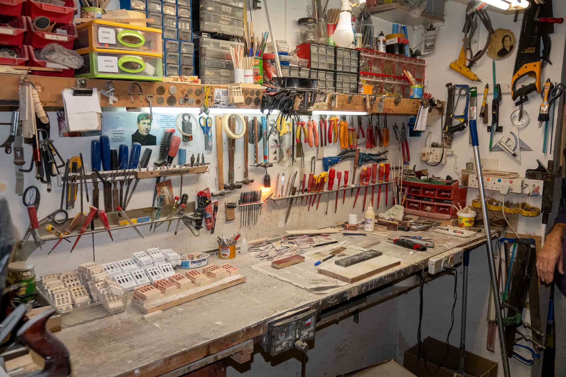 A wall of well-used hand tools in an organized workshop