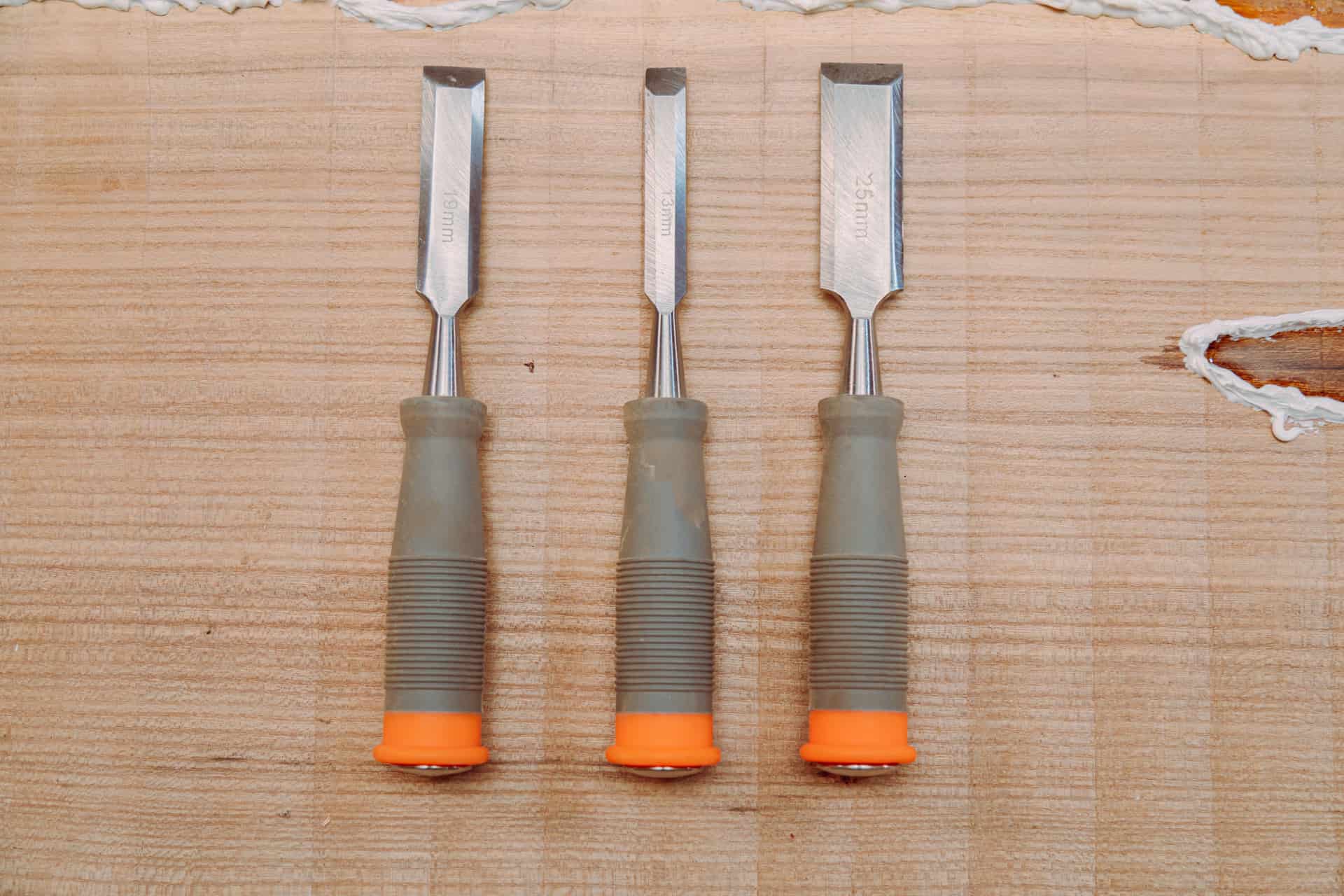 A set of woodworking chisels laid out in a row on a bench