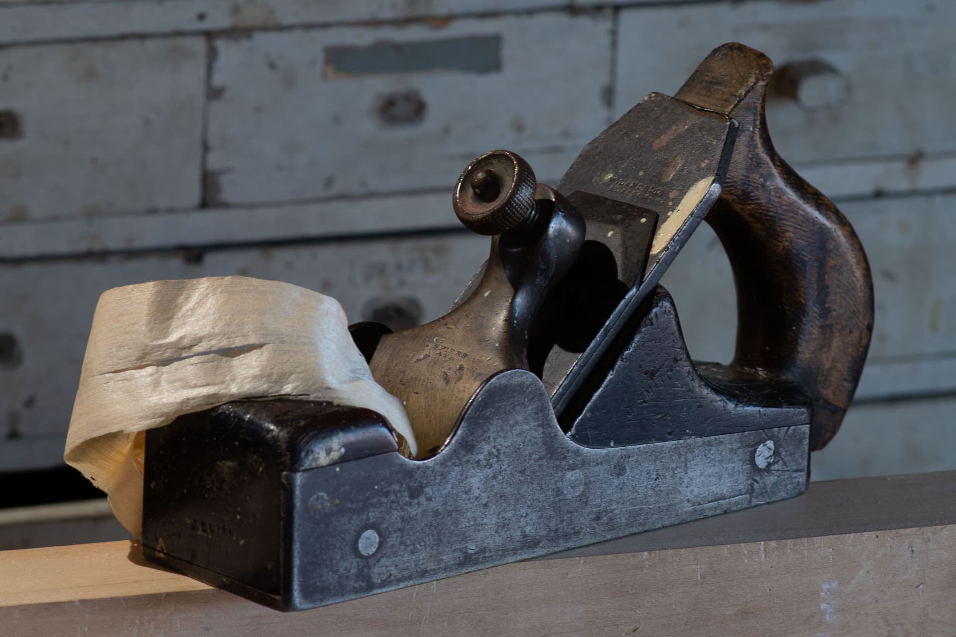A vintage bench plane resting on a wooden workbench in a traditional woodshop
